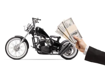 Man hand showing packets of money and a motorcycle in background