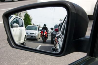 A red, sporty, motorcycle moves between the lane, dangerously close to cars