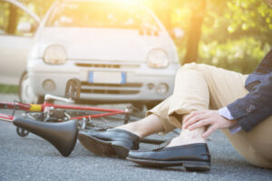 Injured man lying on asphalt in pain after a bicycle accident.