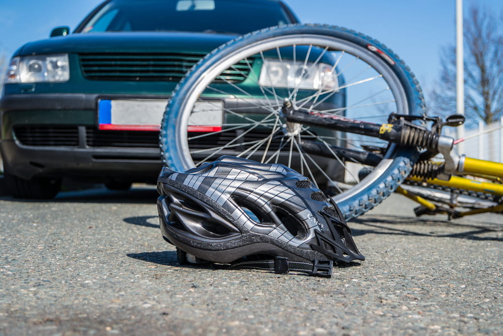 Bicycle accident involving a car with a helmet and damaged bike on the road