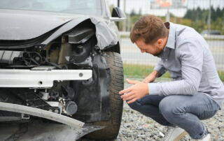 Driver inspecting vehicle damage after a car accident while reviewing insurance claim options in Indiana
