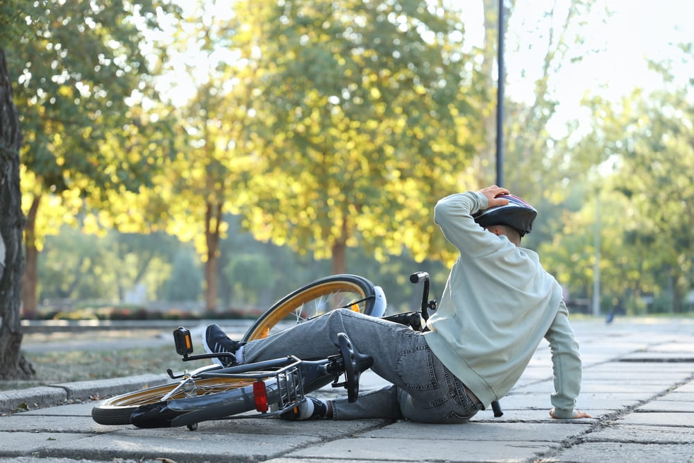 Cyclist sitting on the ground after falling from a bicycle on a public road