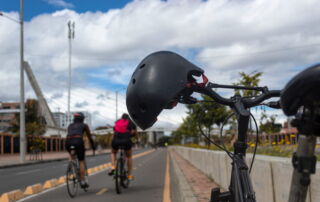 Cyclists riding in a bike lane with a helmet hanging on a bicycle