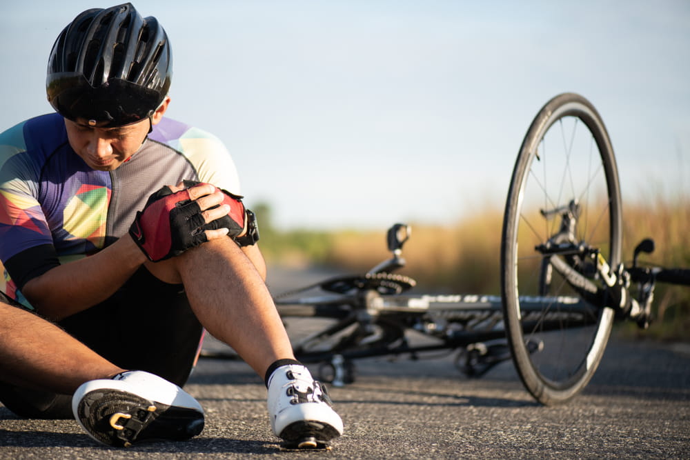 Cyclist holding injured knee after falling in a bicycle accident