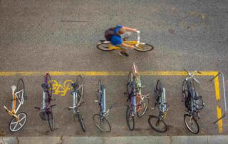 Overhead view of a cyclist riding past a bike parking area on a city street